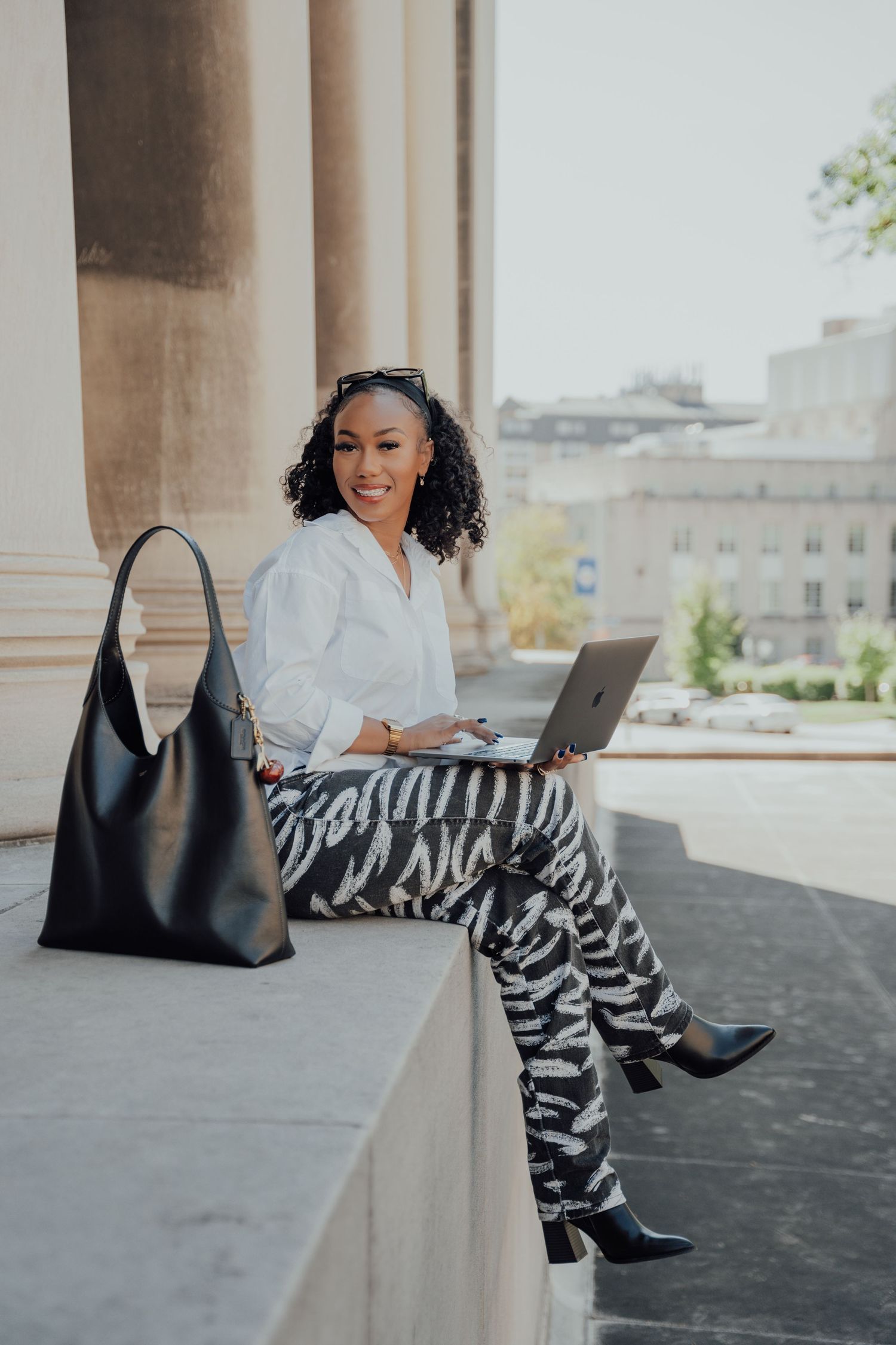 Professional lifestyle photo showing laptop work session on outdoor stone column ledge.