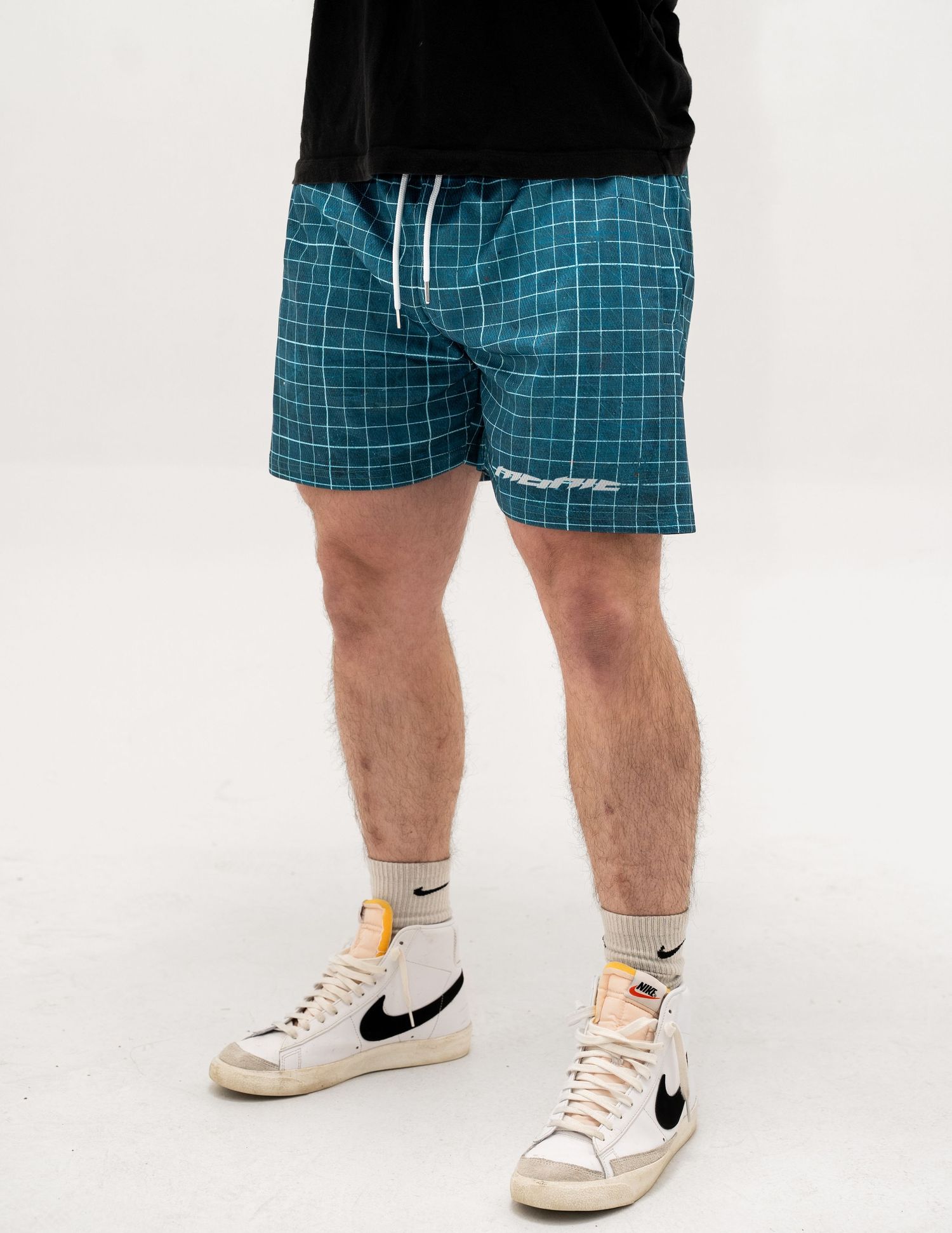 Teal and white checkered pattern shorts with Nike Blazer sneakers on display.
