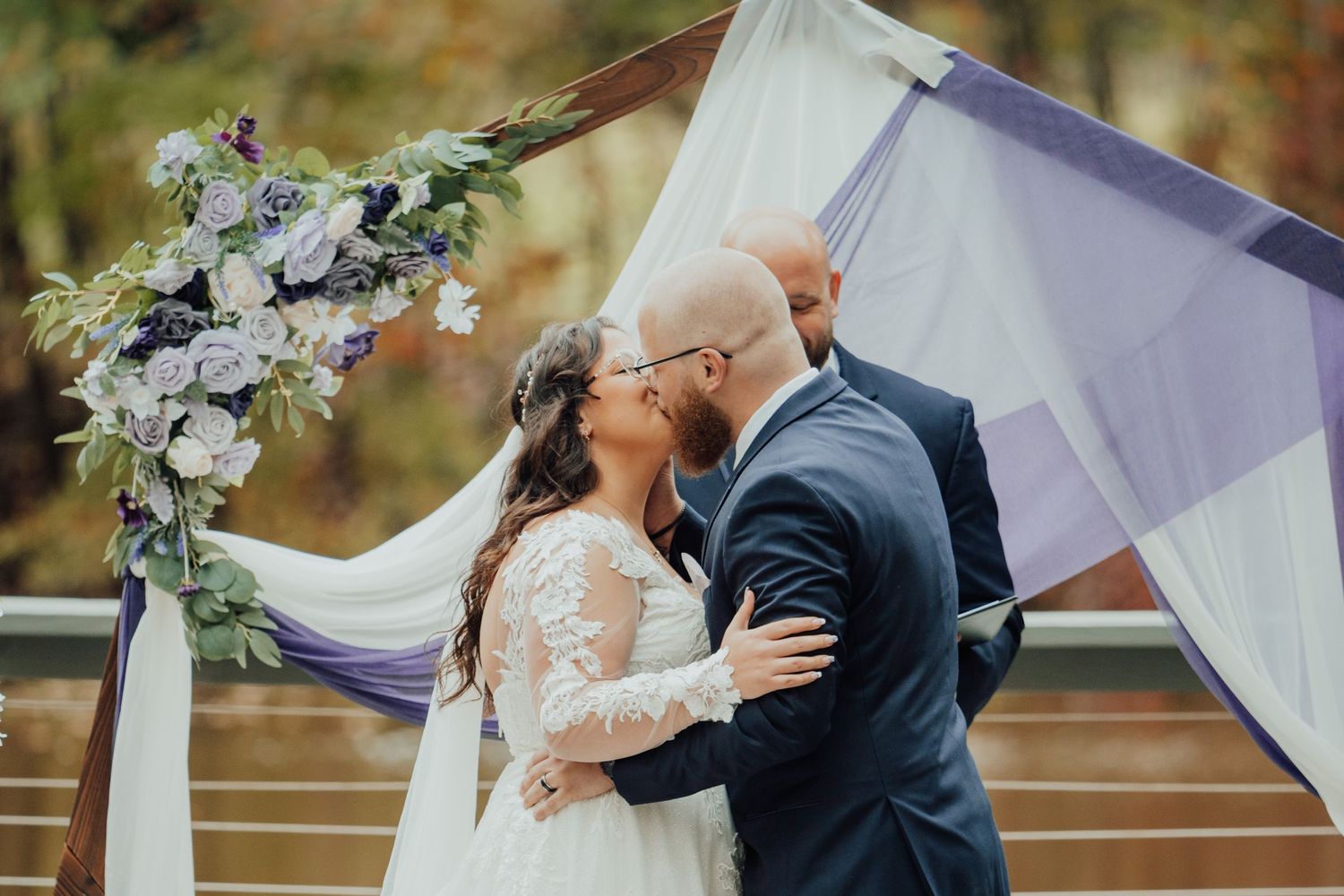 Romantic outdoor wedding scene with flowing white fabric decorations and autumn trees.
