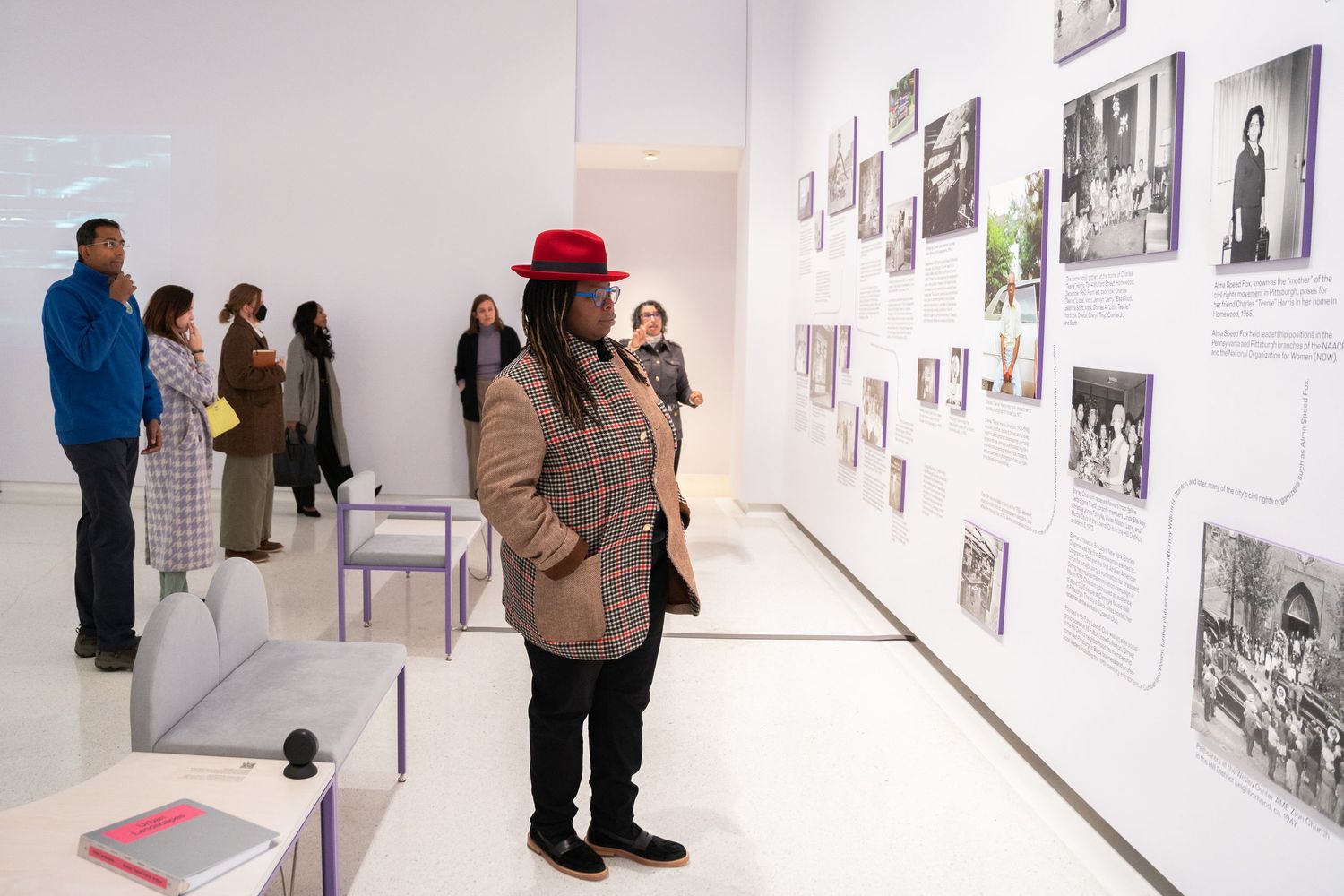 Exhibition visitors examine photographs displayed on white gallery walls.