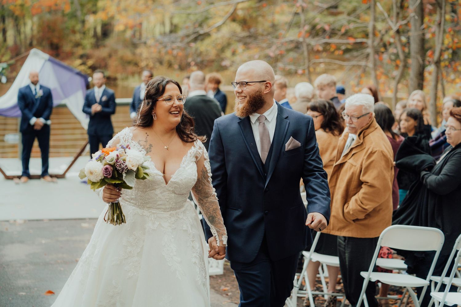 Intimate outdoor wedding celebration surrounded by autumn trees and loved ones.
