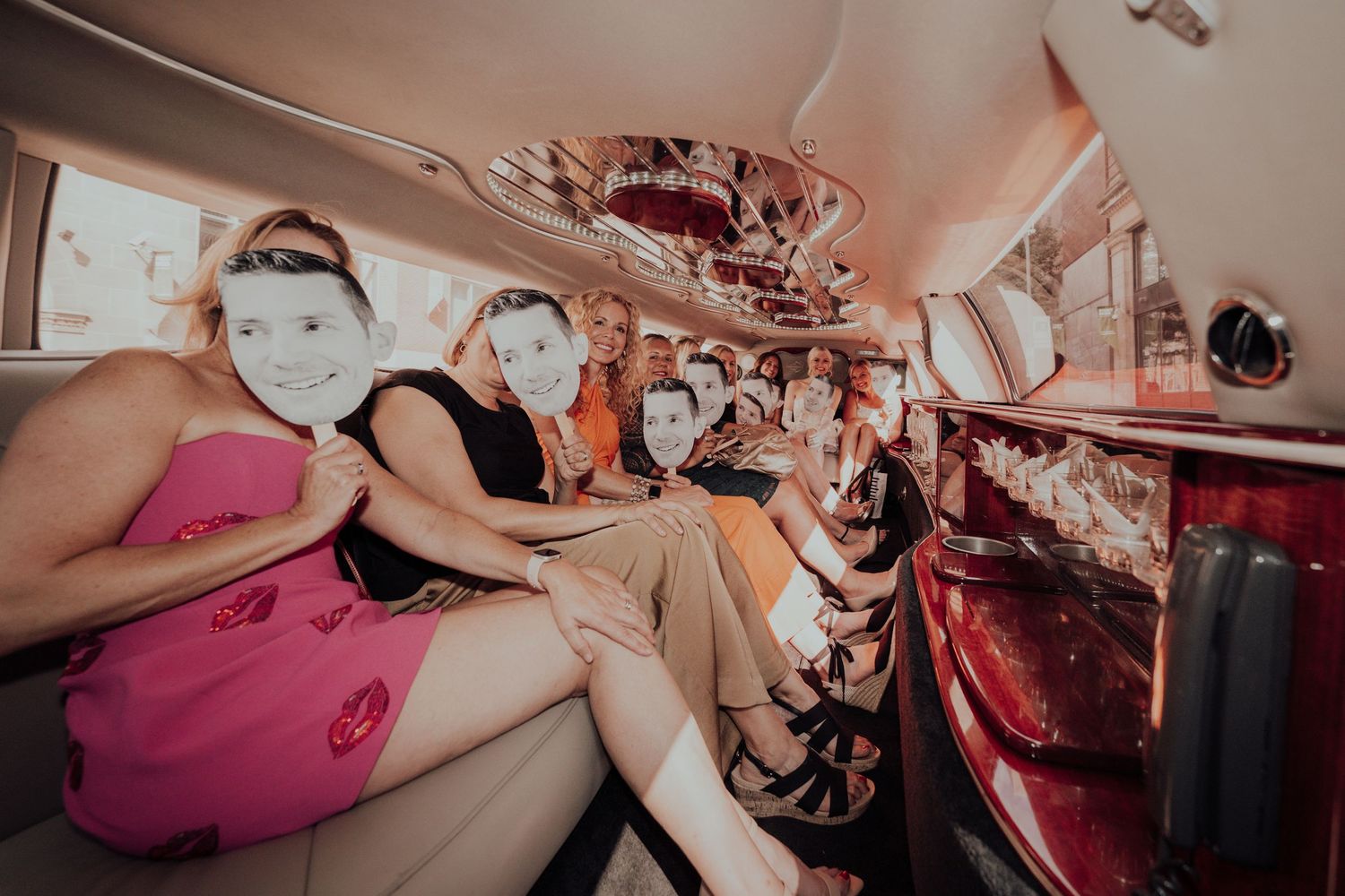 Party goers celebrate inside decorated vintage limousine interior.