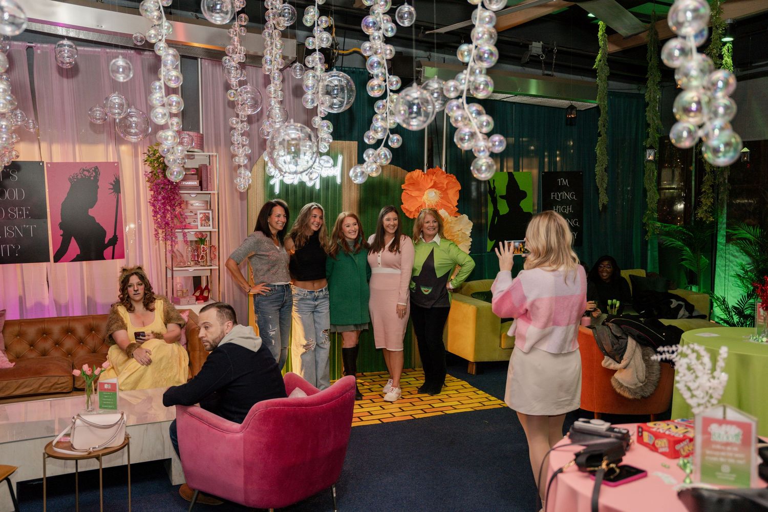 Stylish party venue with hanging crystal decorations, pink furniture, and green ambient lighting.