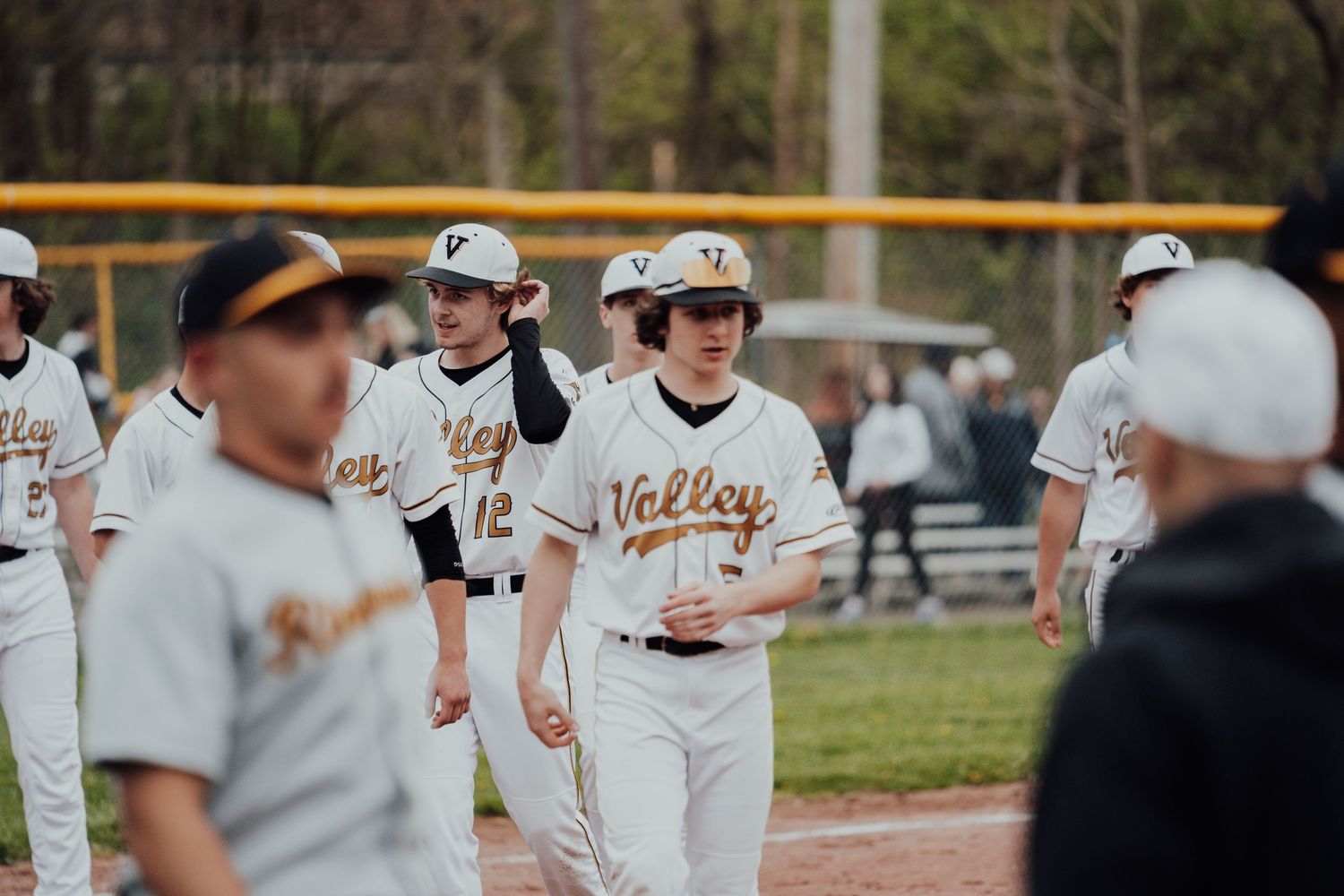 Baseball players in white Valley uniforms gather on field during game.