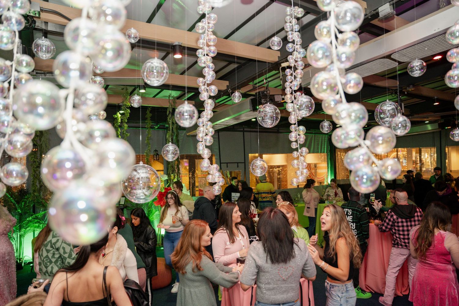 Celebration under hanging glass bubble lights in decorated indoor space.