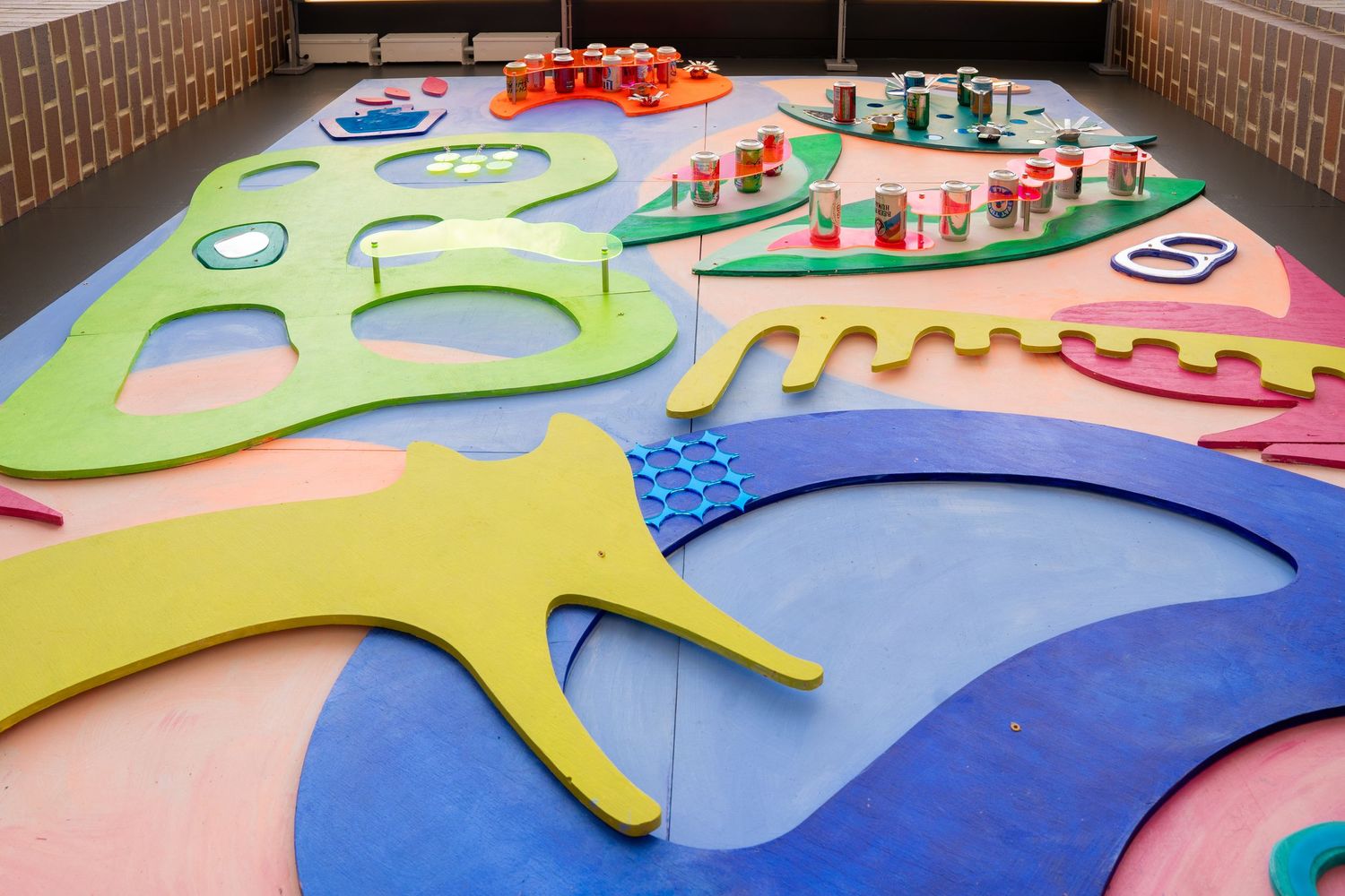 Colorful abstract floor art installation with geometric shapes and raised platforms in an indoor space.