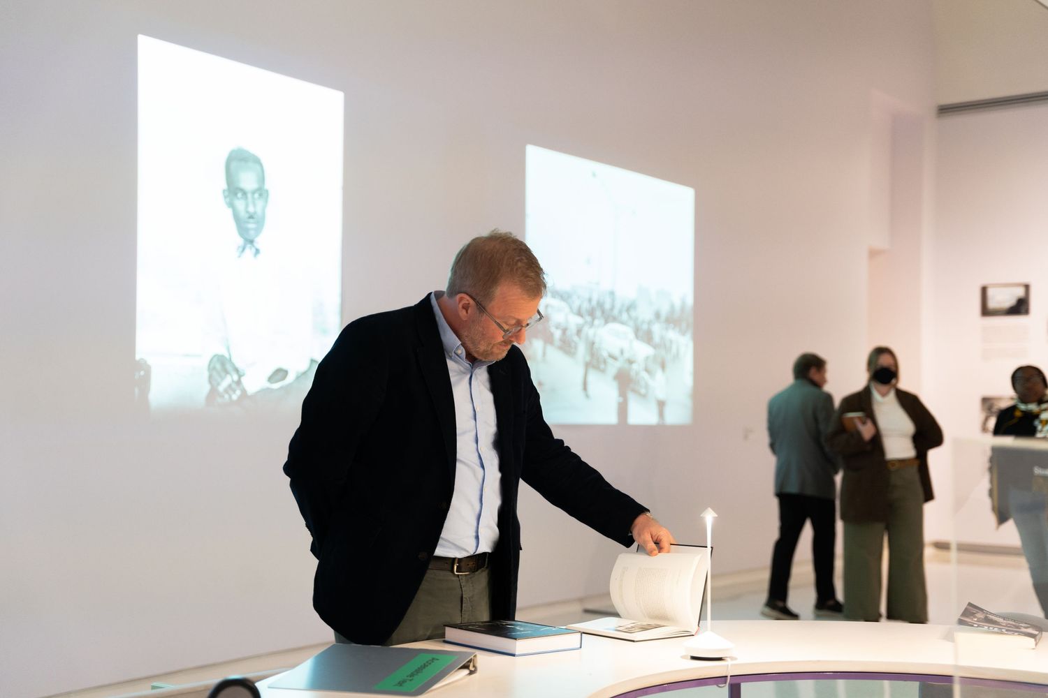 Visitors view projected images in a minimalist gallery space with white walls.