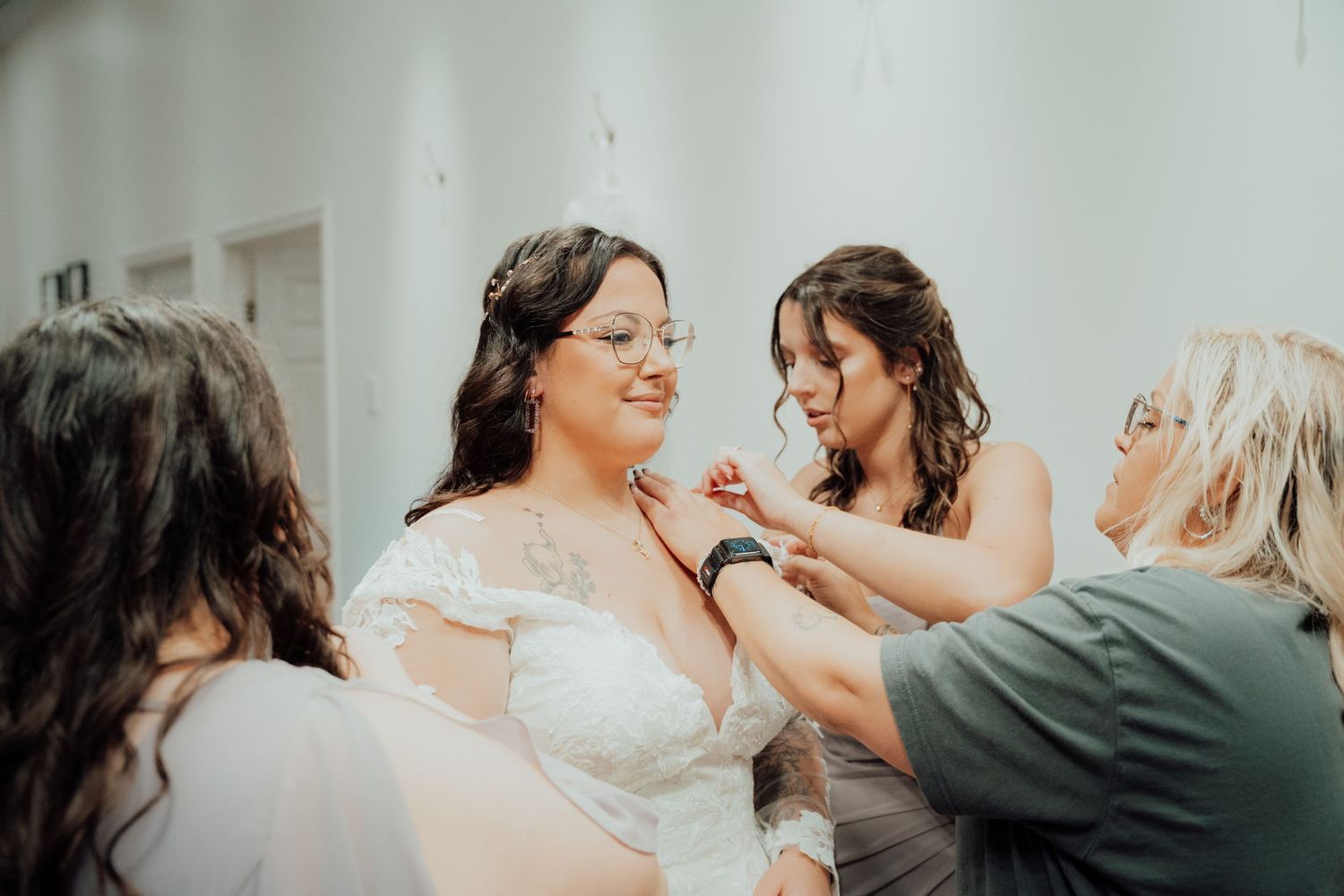 Wedding preparation scene with bride getting final touches from helpers in bridal suite.