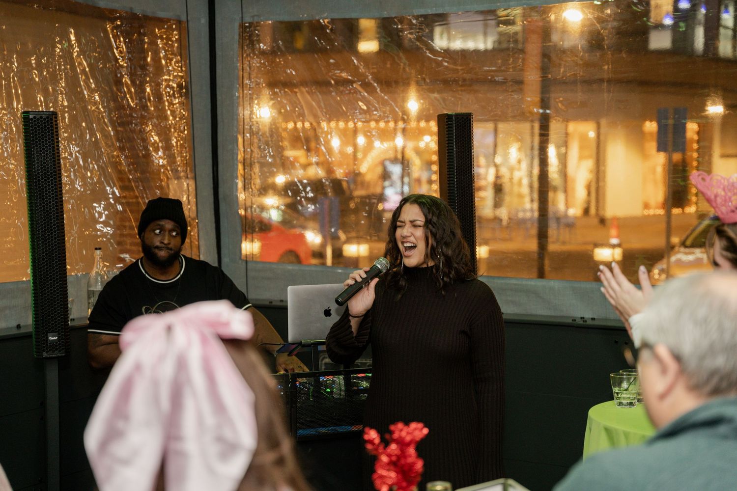 People enjoying an indoor entertainment event with festive string lights in the background.