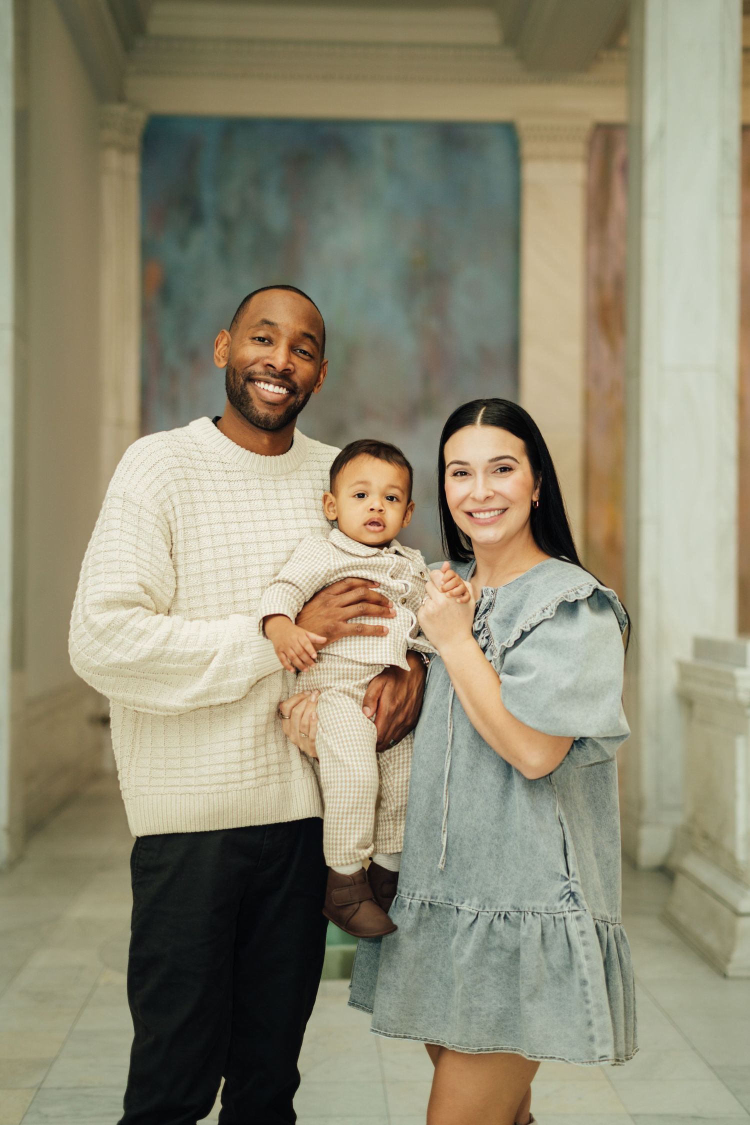 A family poses together in a series of four connected photos showing tender moments in a light-filled hallway.