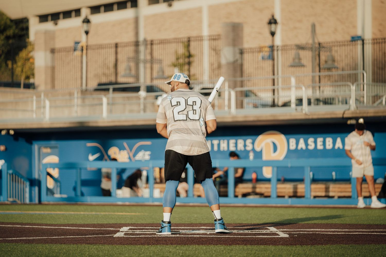 Baseball player delivers pitch from mound during competitive game on sunny afternoon at outdoor stadium.