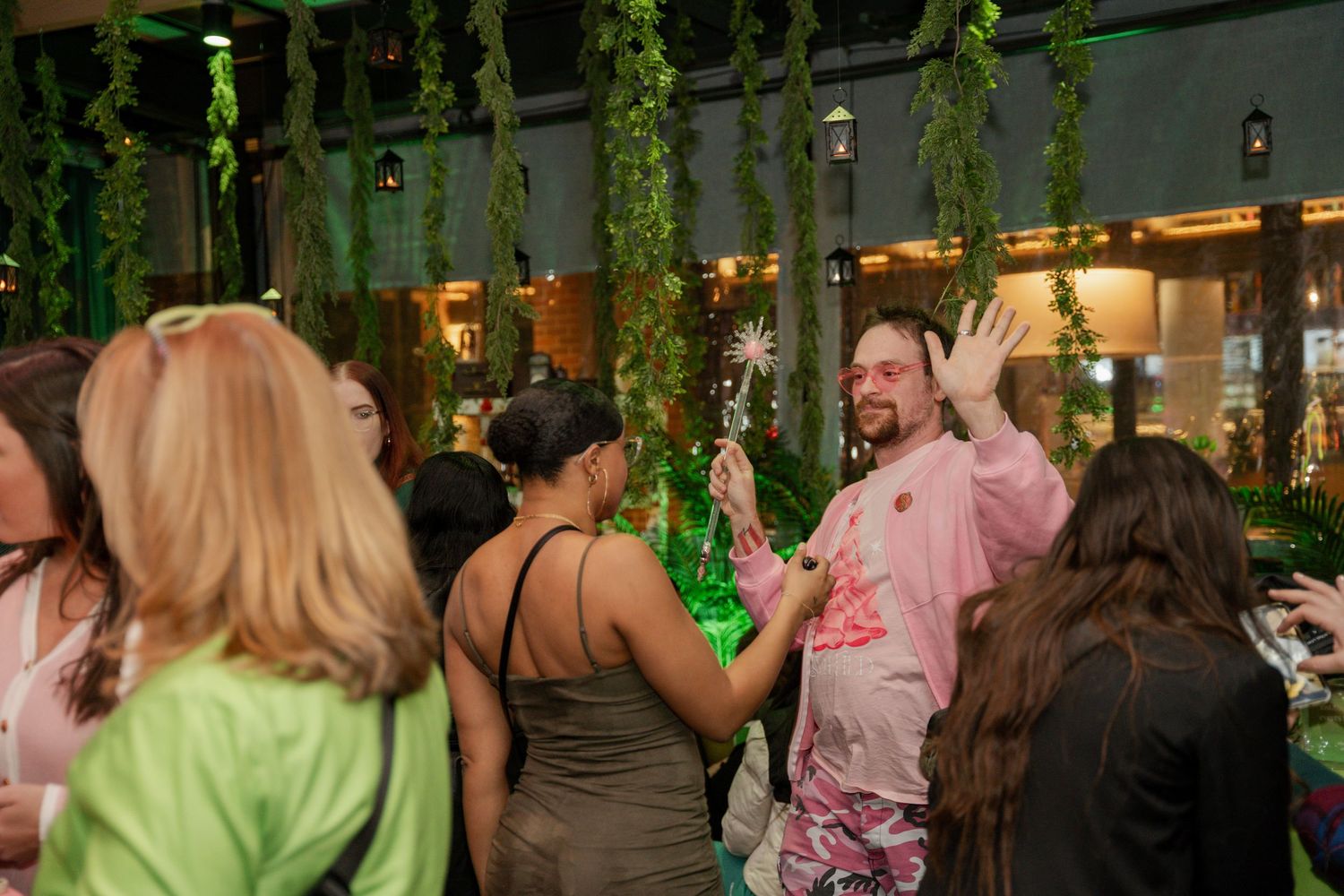 Social gathering under hanging greenery with mood lighting.