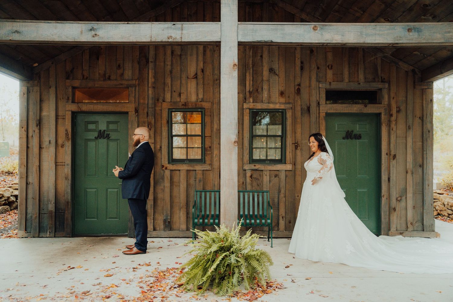 A rustic wedding venue exterior with green doors and wooden siding.
