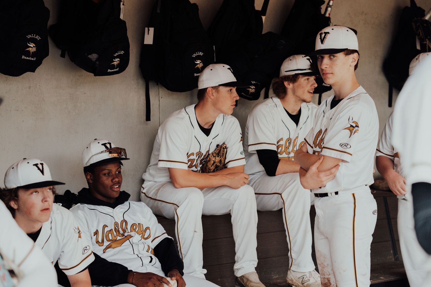 Baseball team dugout filled with players in white uniforms during a game.