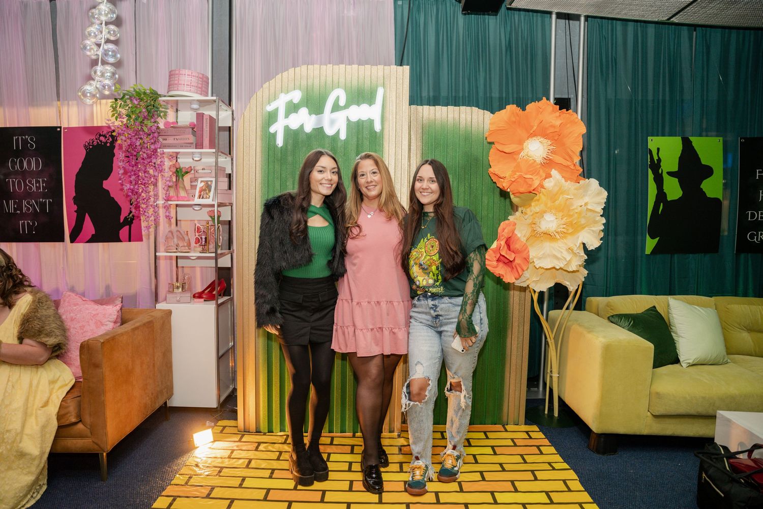 Friends pose on yellow brick road set with neon signage and floral decorations.