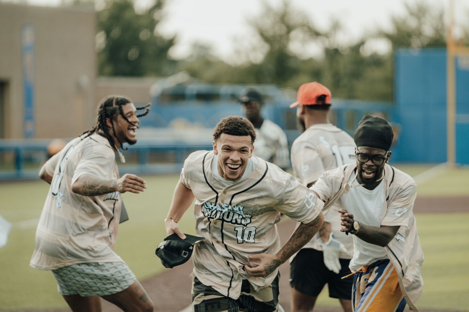 Baseball teammates celebrating and running together on a field during what appears to be a joyful moment.
