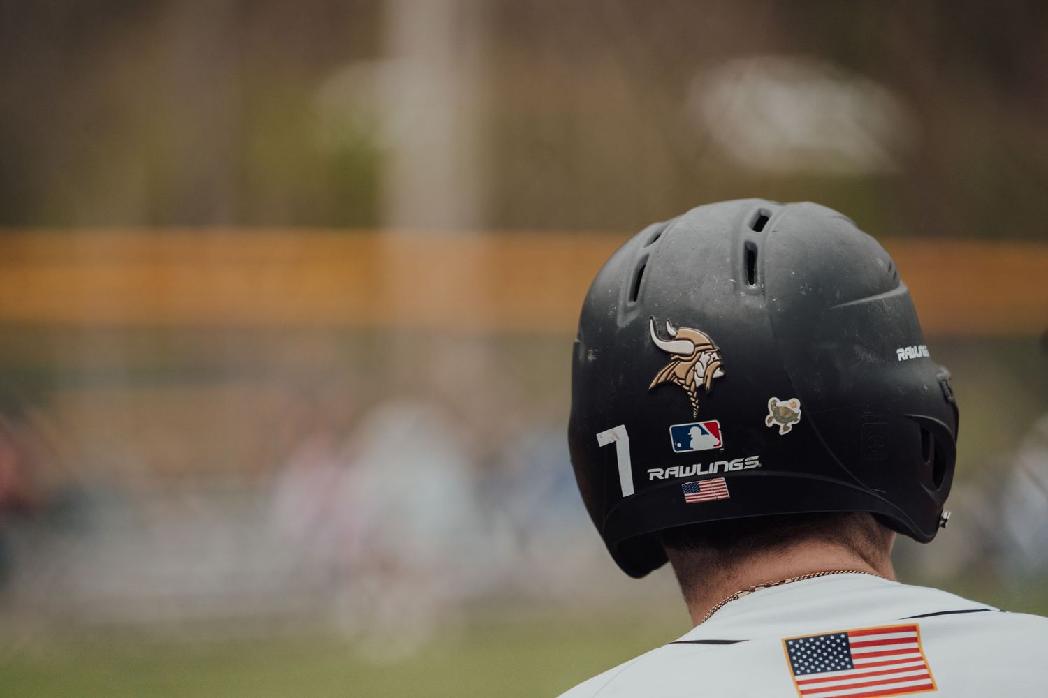 Baseball players wearing protective helmets watching from the dugout during a game.
