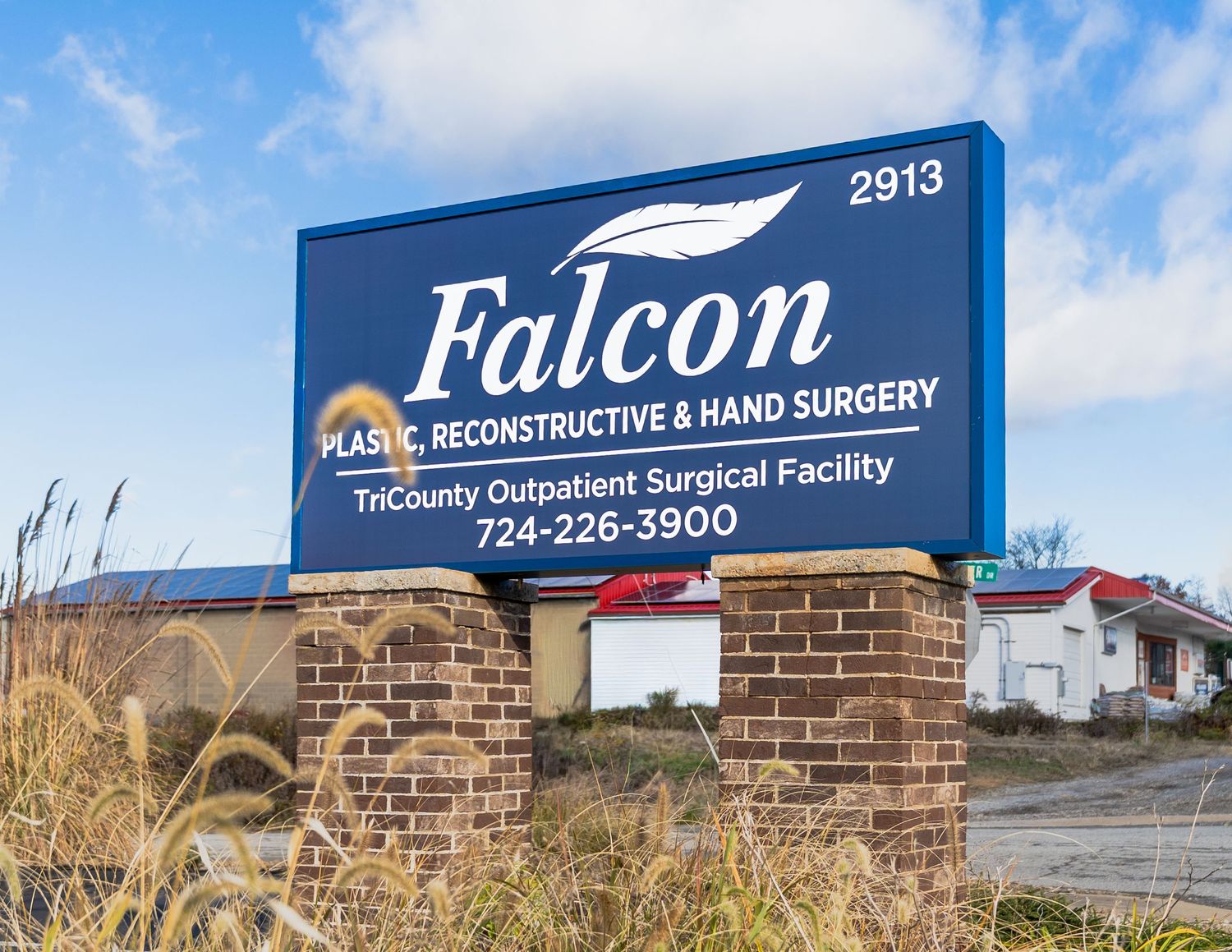 Exterior signage of Falcon Reconstructive & Hand Surgery medical facility with brick facade and blue sky background.