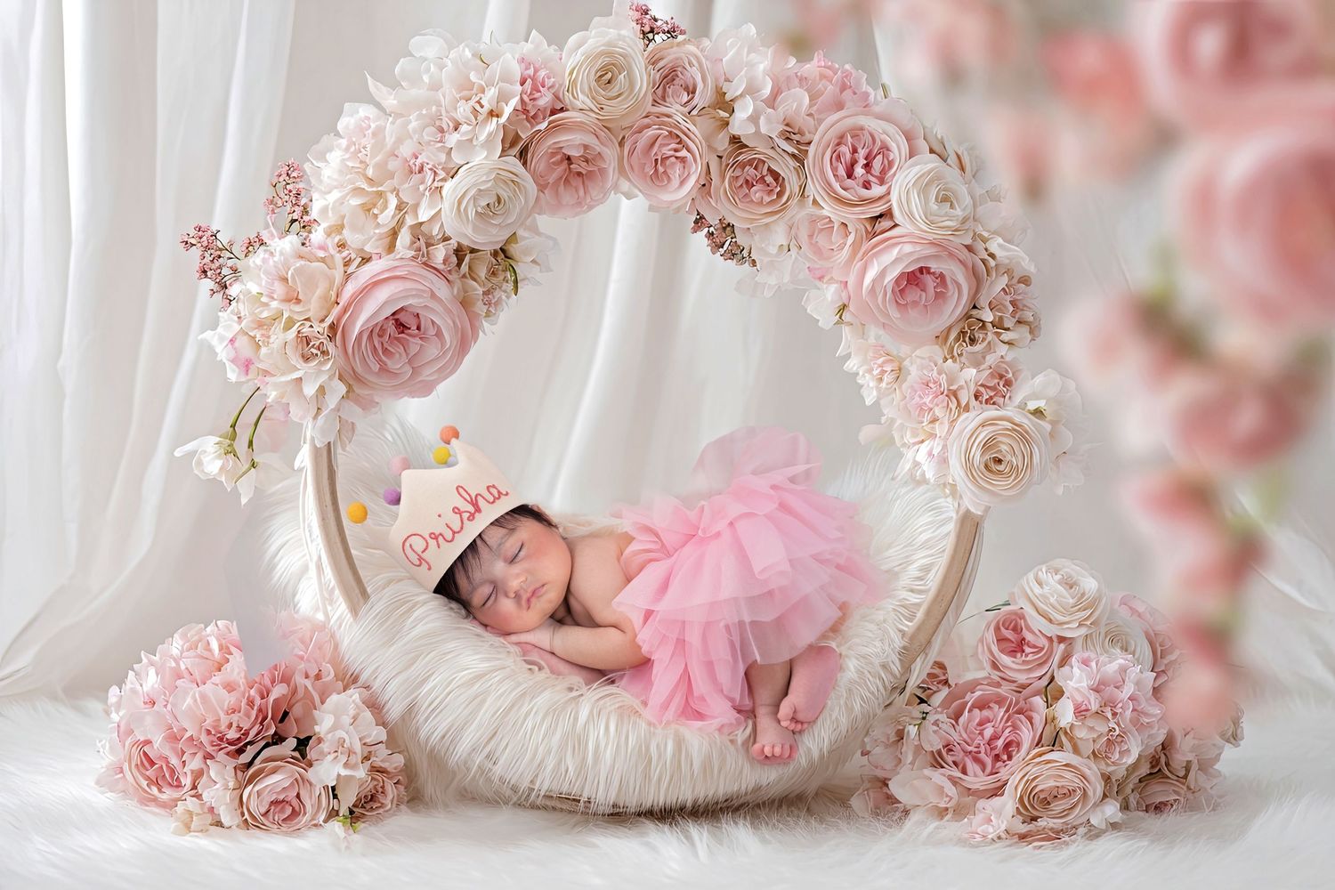 Newborn baby sleeping in a floral wreath bowl with pink roses and white flowers, wearing a pink tutu skirt.