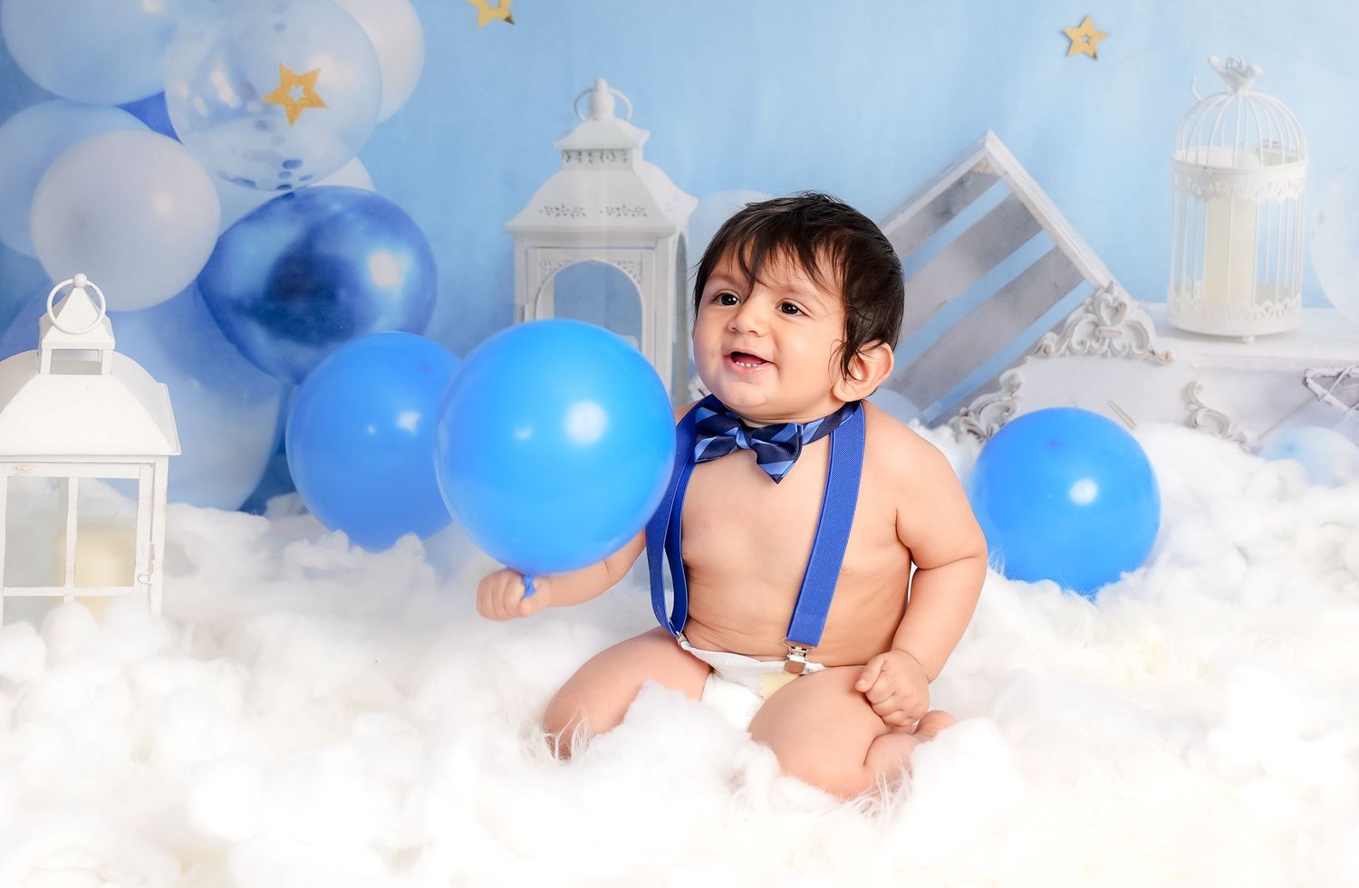 Blue and white balloon decorations create a dreamy atmosphere for a first birthday celebration with cake and treats.
