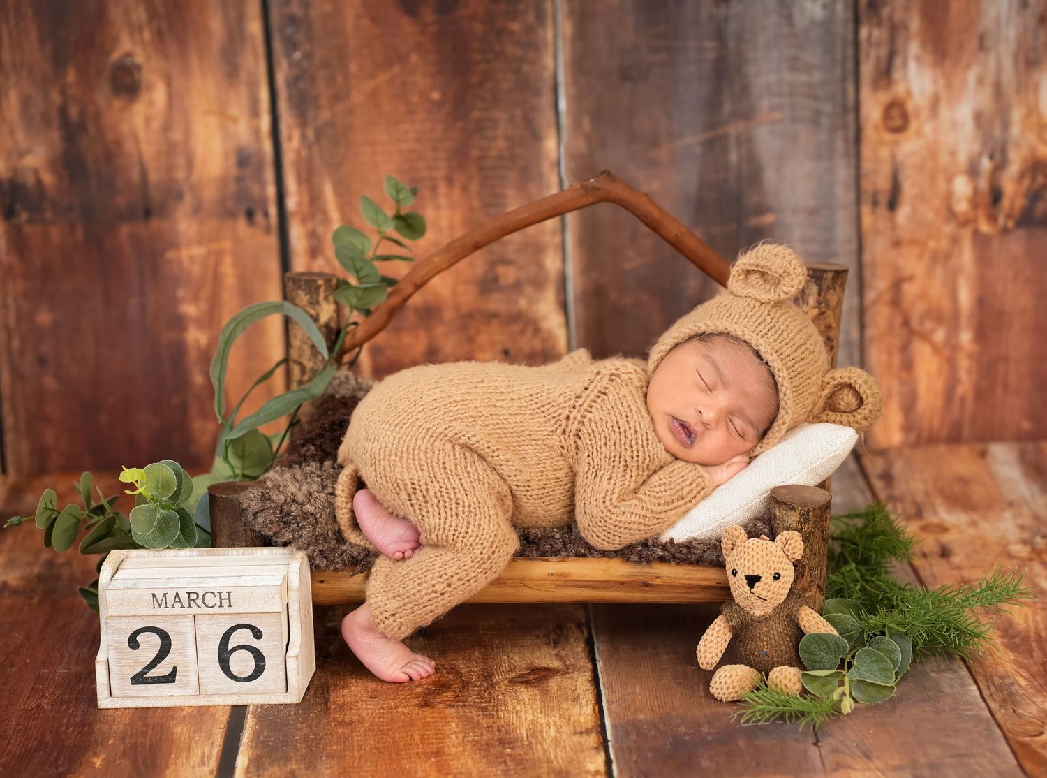 A rustic wooden backdrop with greenery and a vintage calendar showing March 26.