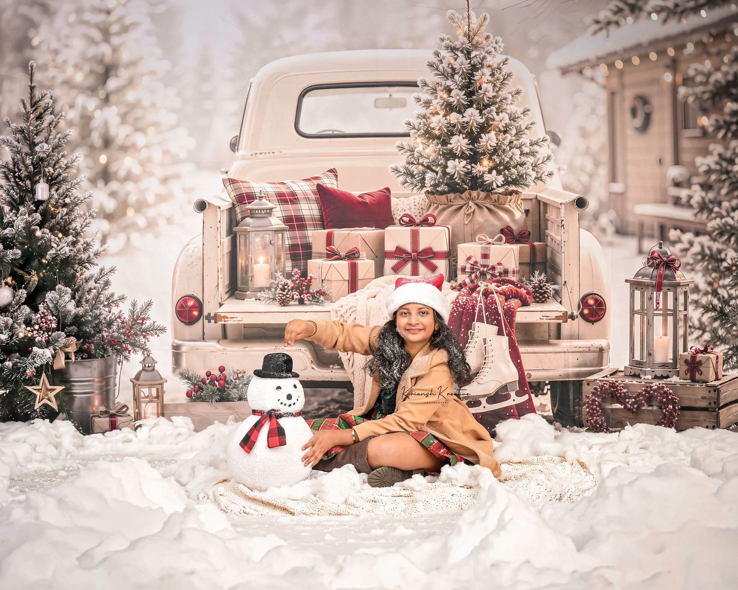 Child in Santa hat sits with snowman toy near vintage truck with Christmas gifts and snowy trees.