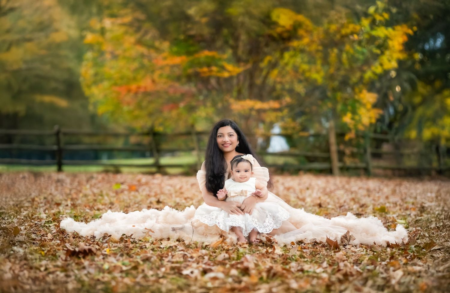 A formal portrait taken outdoors with autumn foliage and fallen leaves on the ground.