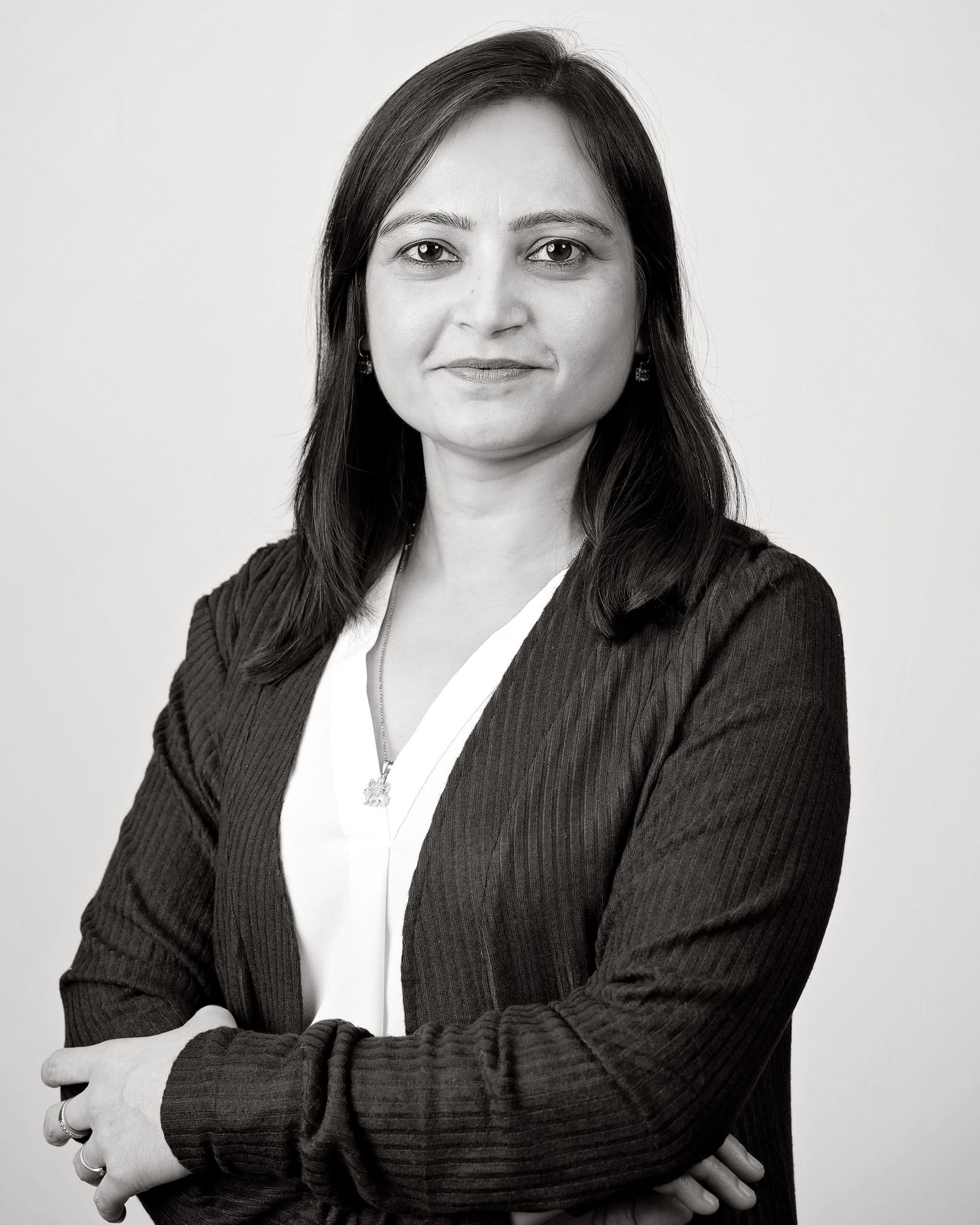 Professional headshot of person in black business suit against white background in four similar poses.