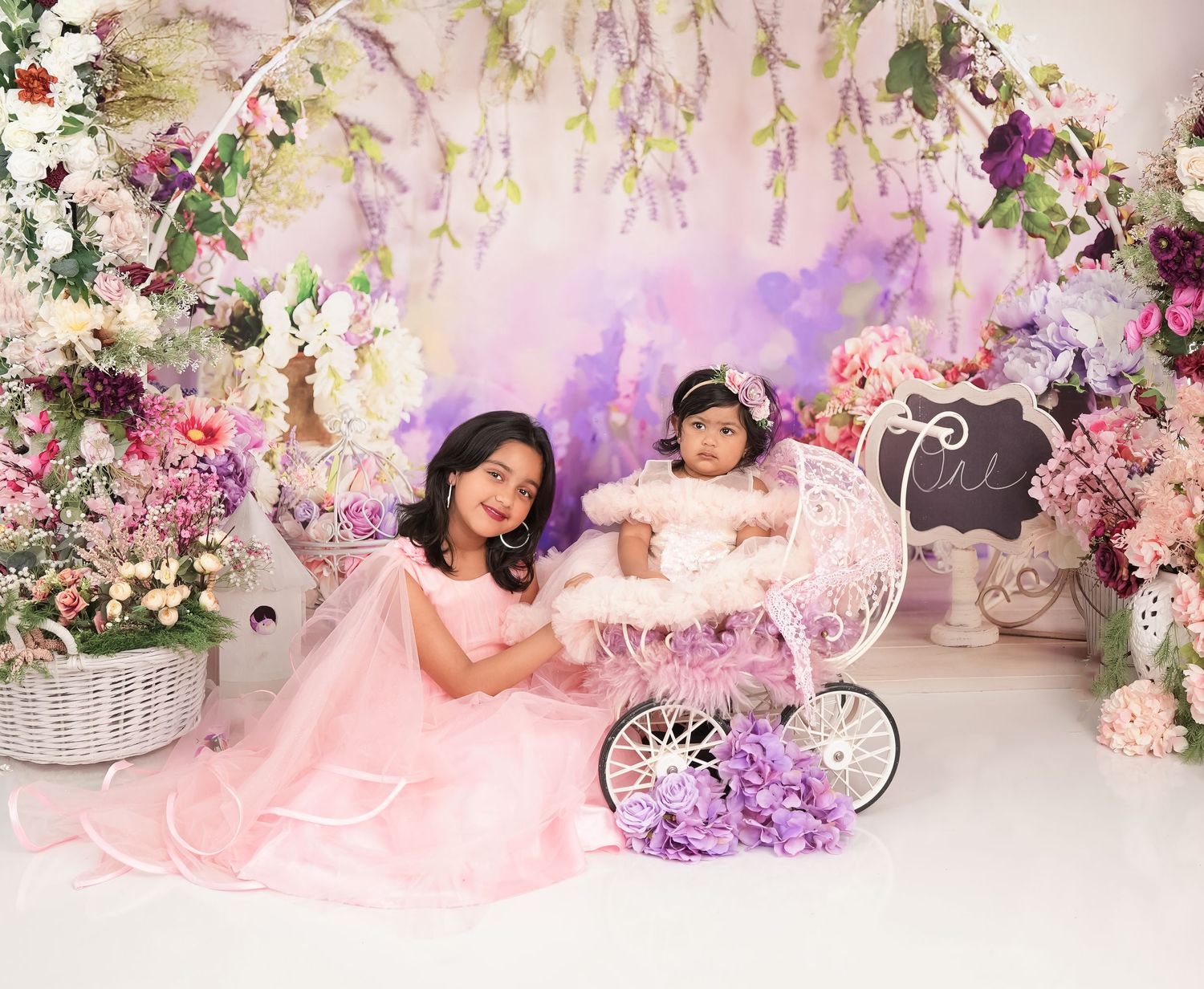 Elegant pink and purple floral backdrop with vintage white carriage surrounded by blooming flowers and soft lighting effects.