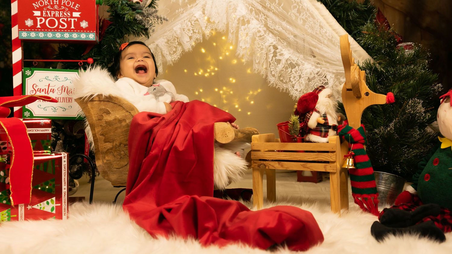 A cozy Christmas scene with red stockings, decorative lights and Santa-themed decor around a festive holiday display.