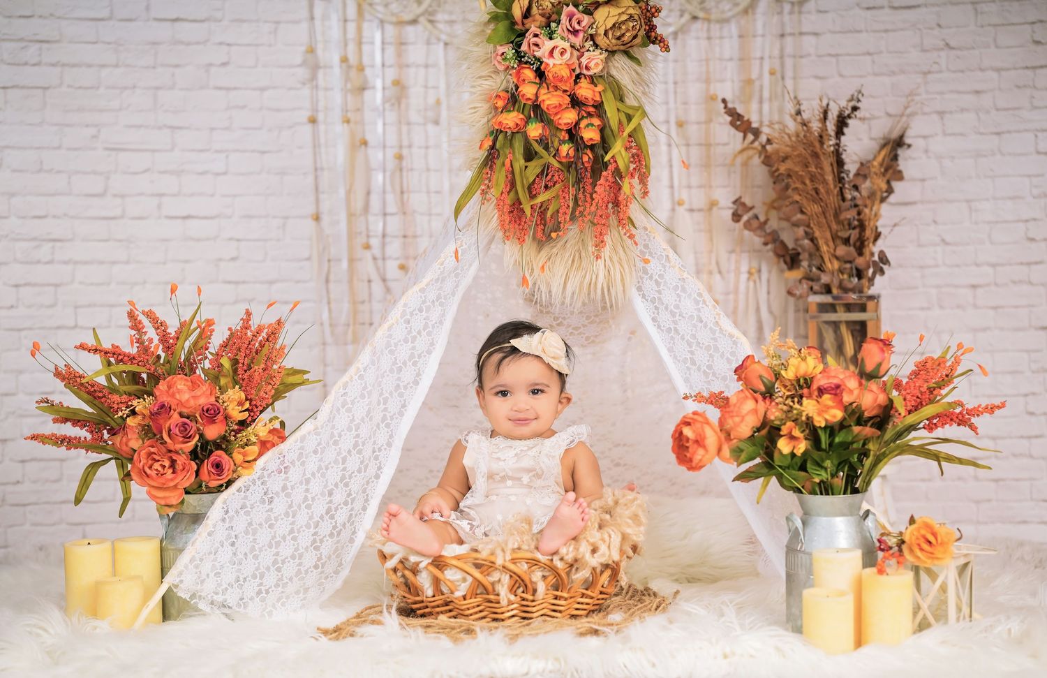 Autumn themed photography backdrop with peach flowers, dried pampas grass and rustic hay bales against white brick wall.