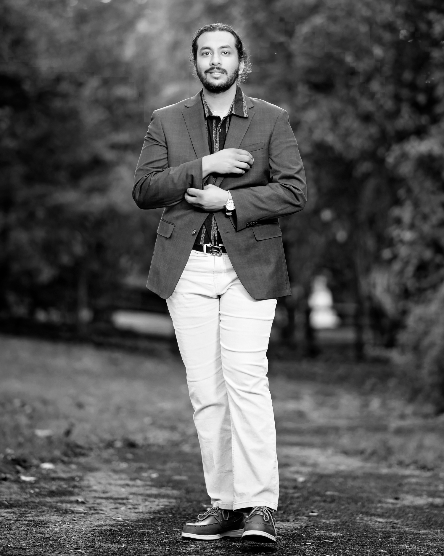 A series of black and white portraits showing a person in white pants and dark jacket standing outdoors in a park setting.