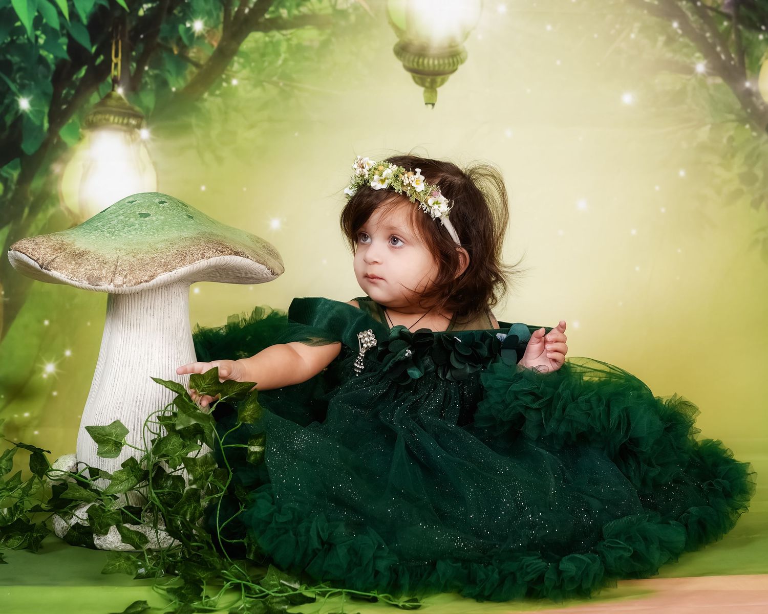 Enchanted forest scene with large mushroom decor and small figure in emerald green tulle dress and flower crown.
