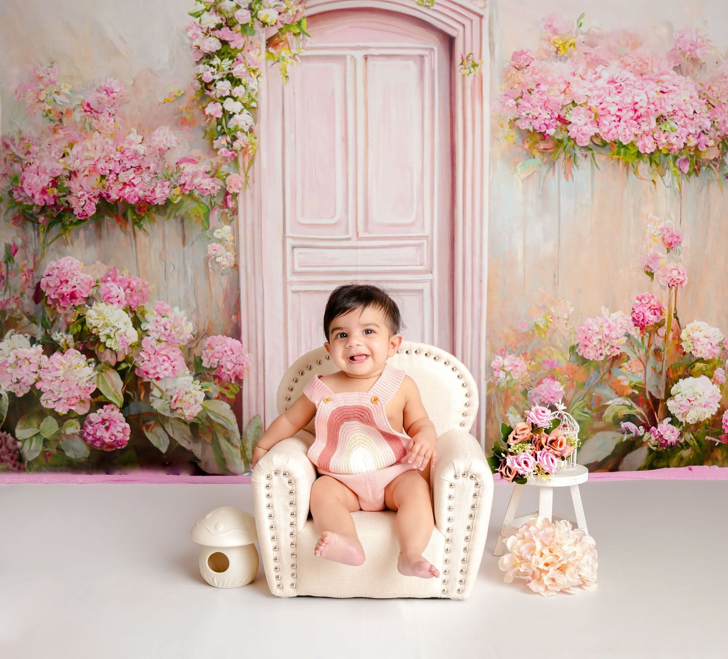 Pink floral backdrop with cream-colored furniture creates a romantic setting for newborn photography sessions.