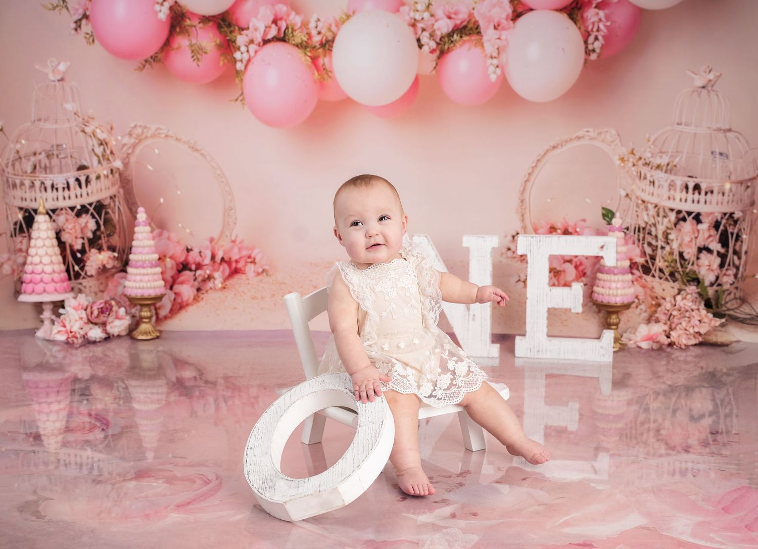 Pink birthday party setup with balloons, cake smash decorations, and white teddy bear in a whimsical first birthday theme.