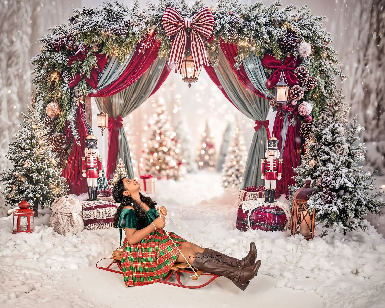 Girl in plaid dress poses under festive Christmas arch with nutcrackers, snowy trees, and red curtains in holiday scene.
