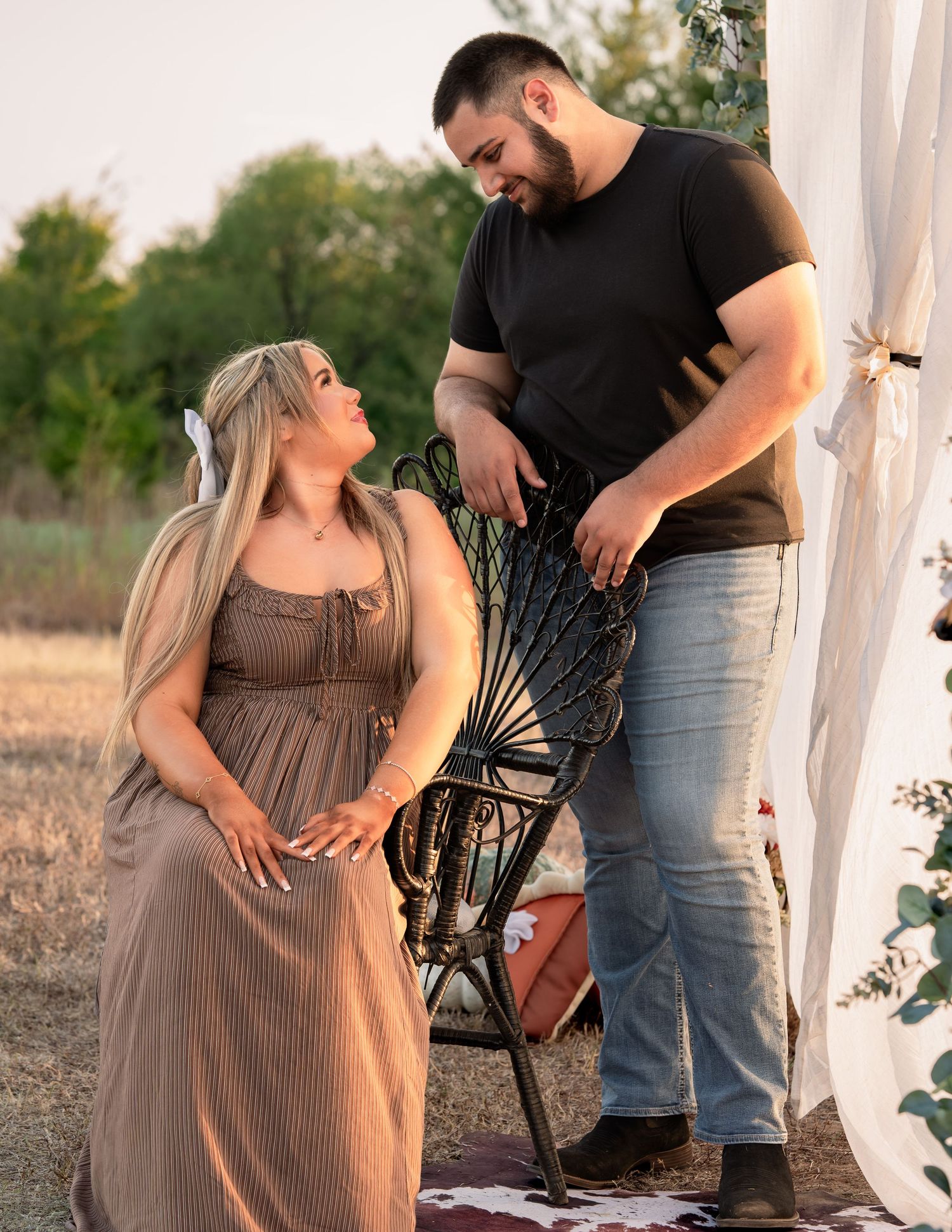 Smiling couple sharing a tender moment during outdoor maternity photography session at golden hour.
