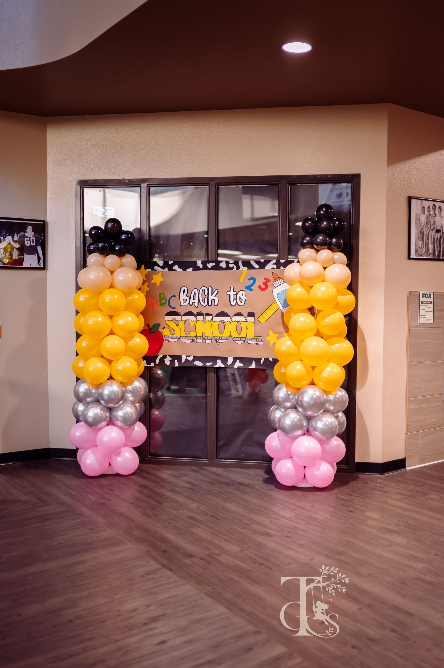 Colorful back to school balloon arch display with yellow, silver, pink and black balloons.