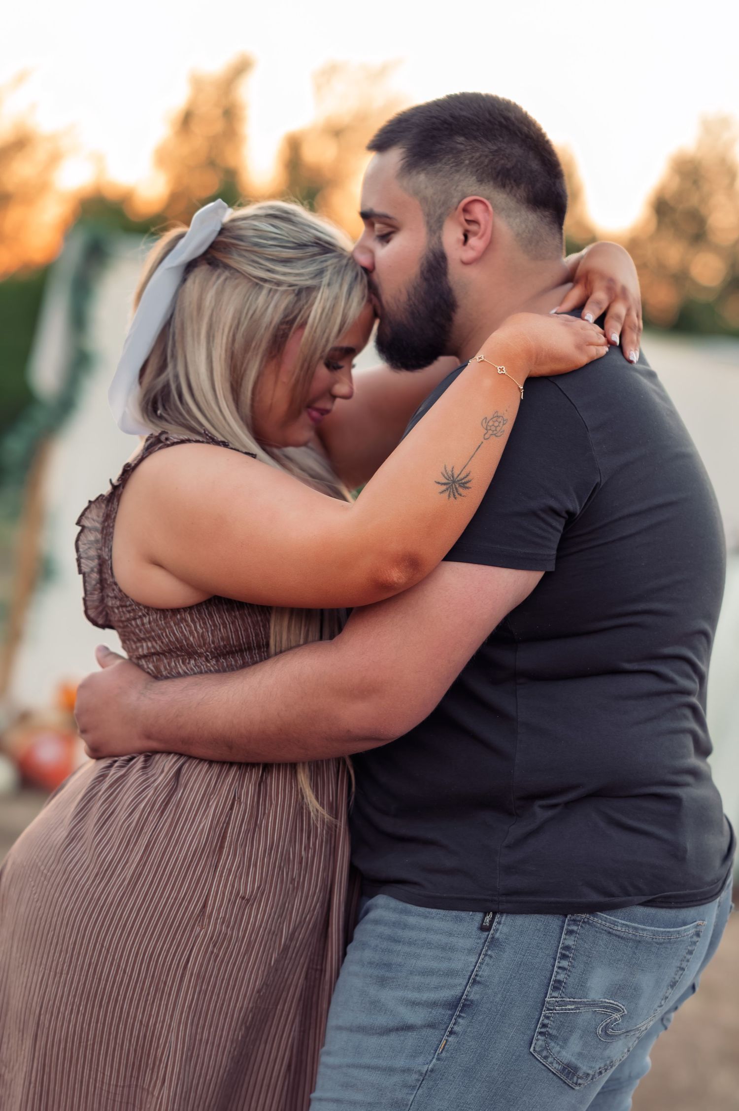 Couple embracing tenderly at a pumpkin patch with warm sunset lighting.