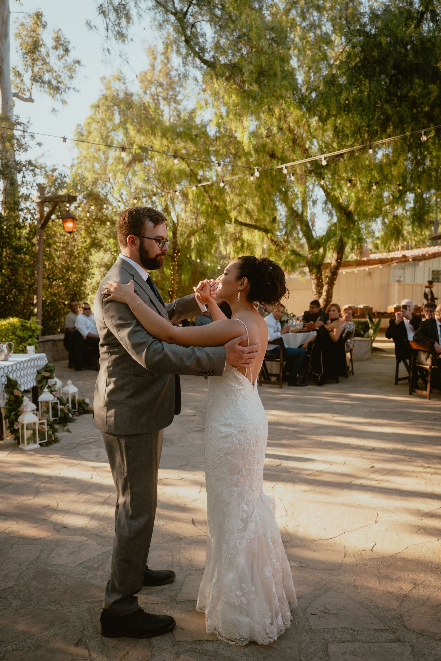 Bride and groom sharing first dance at golden hour outdoor wedding reception.