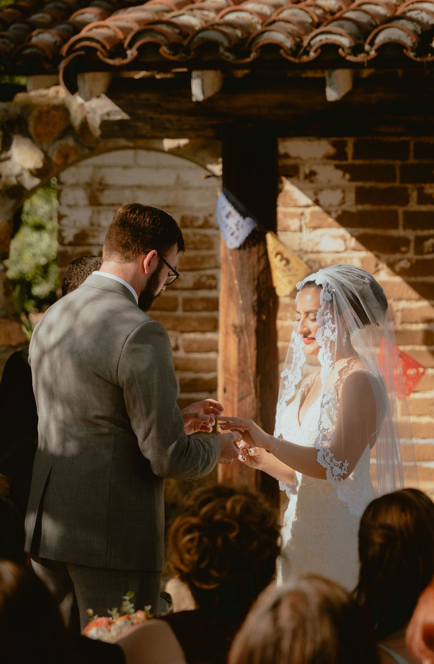 Groom places wedding ring on brides finger during an intimate ceremony exchange of vows.