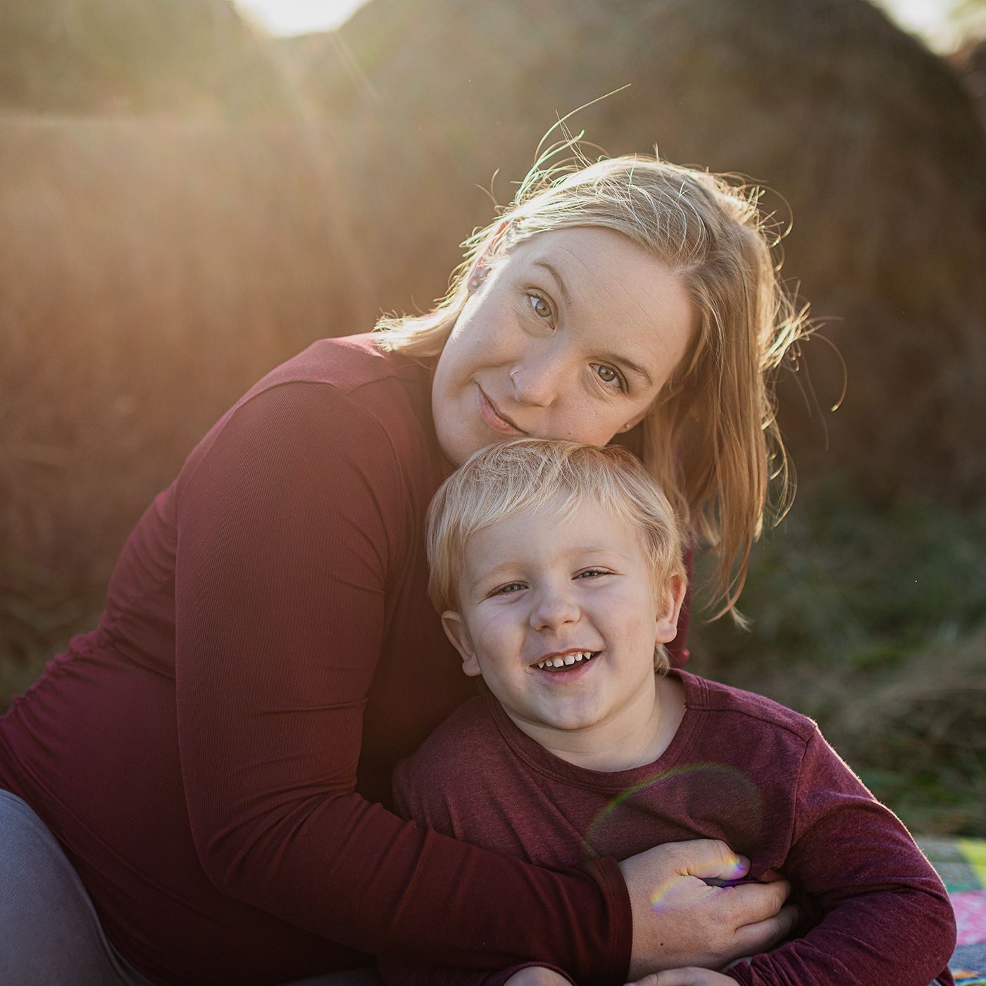 mother and son sitting together in a sunset, country setting