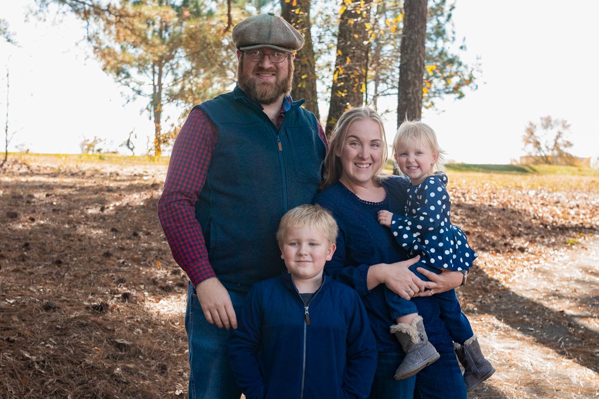 family of four together in an autumn wooded area