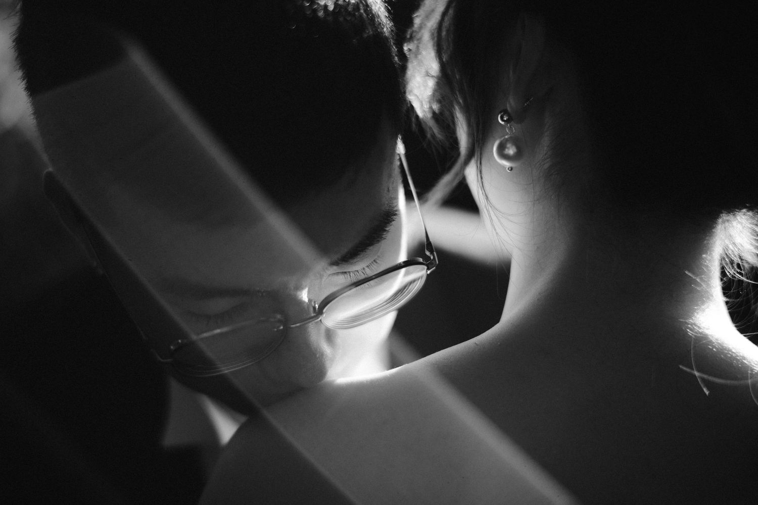 Black and white photo of two people sharing an intimate moment, with dramatic light streaks crossing the frame.