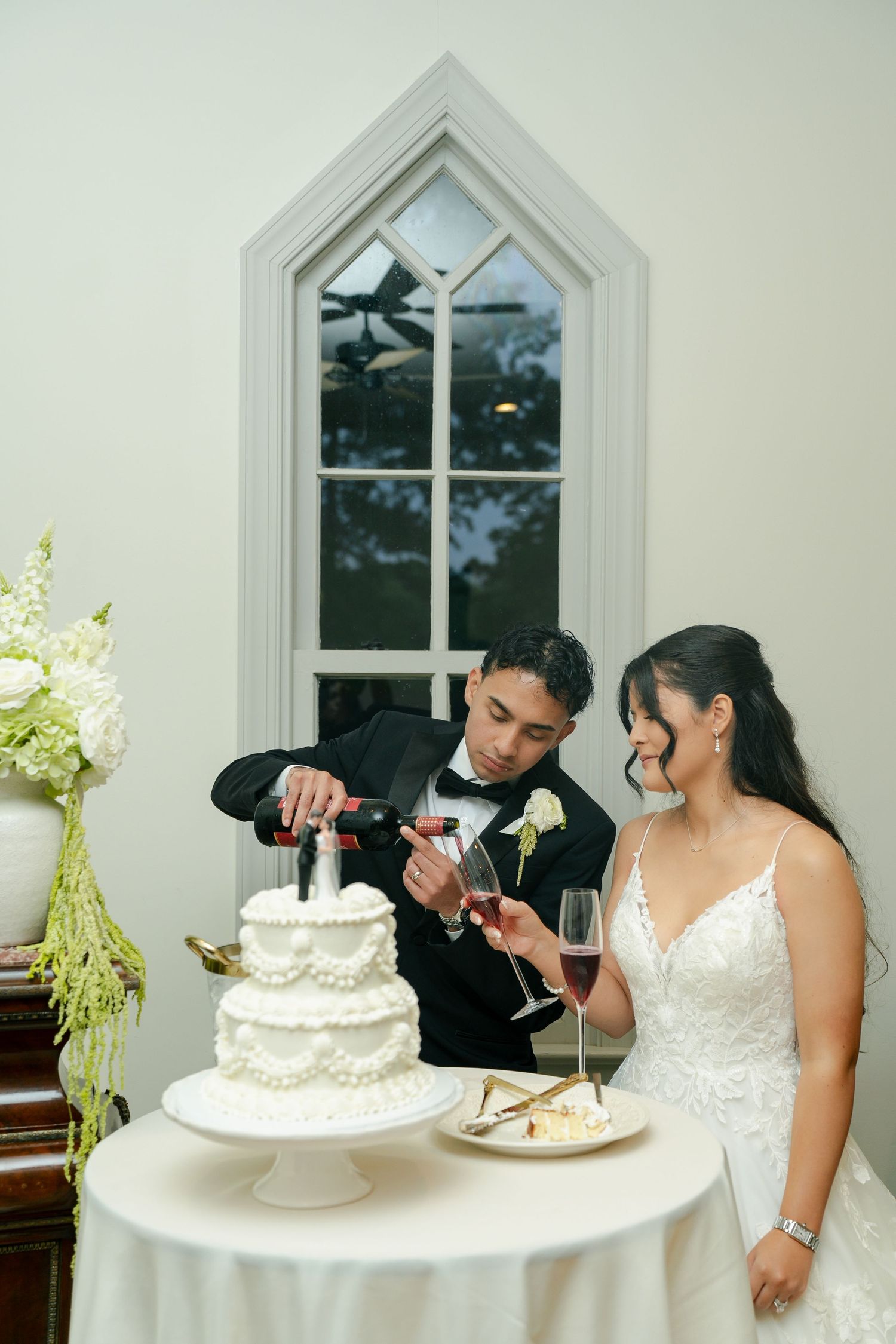 Bride and groom pouring a glass of wine to toast during their cake cutting photos during their reception
