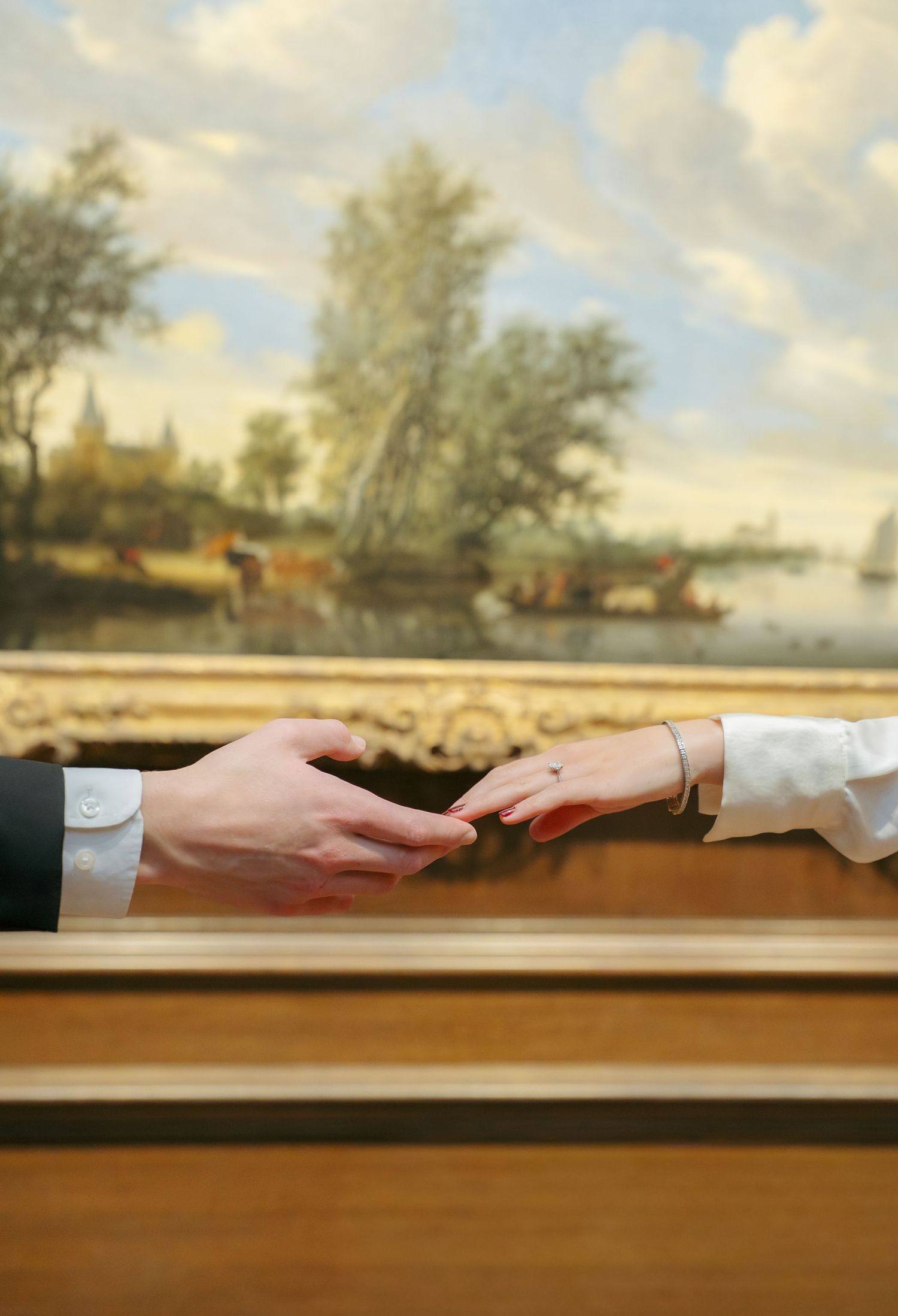 Close-up of an engaged couple holding hands during a romantic museum engagement photography session.