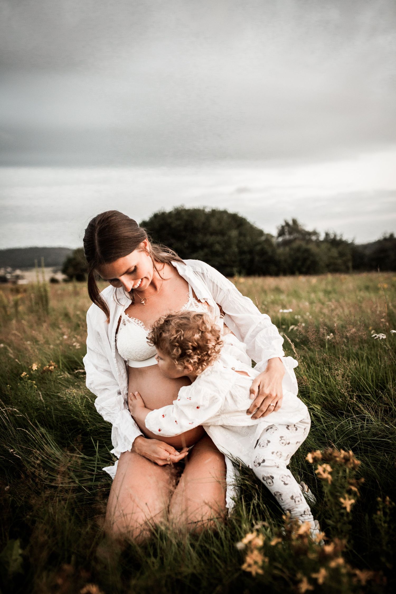 Intimate outdoor portrait in a meadow with moody sky background.