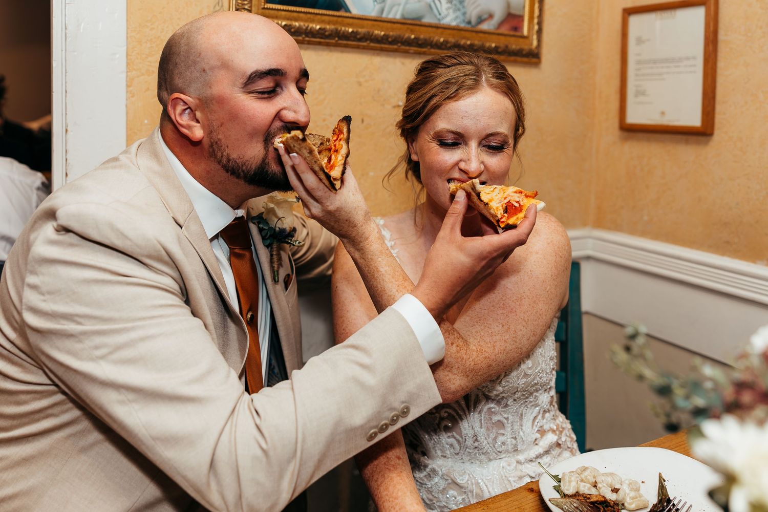 A fun moment as a couple bites into pizza during their wedding celebration.
