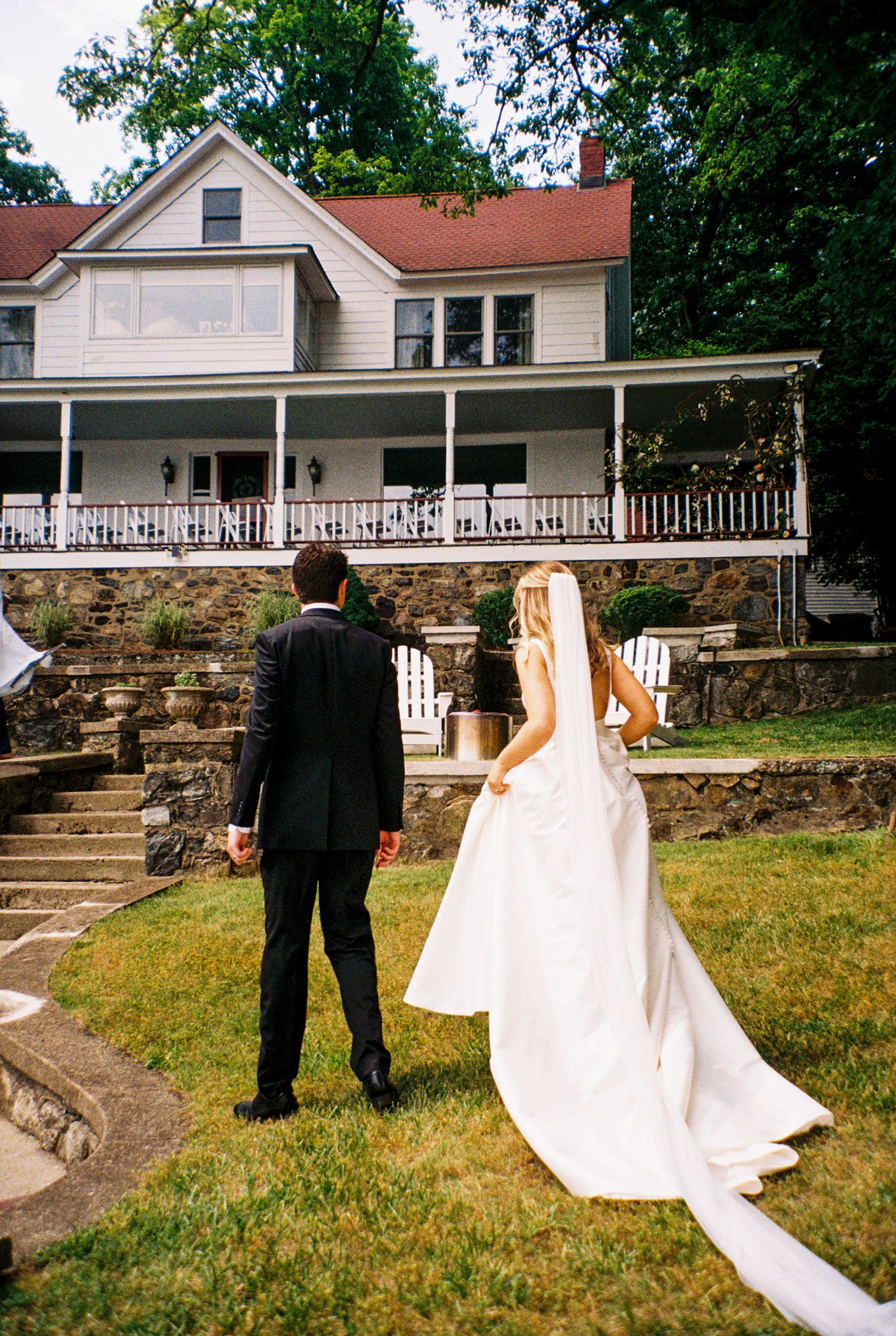 A white farmhouse with wrap-around porch serves as backdrop for a special outdoor celebration.