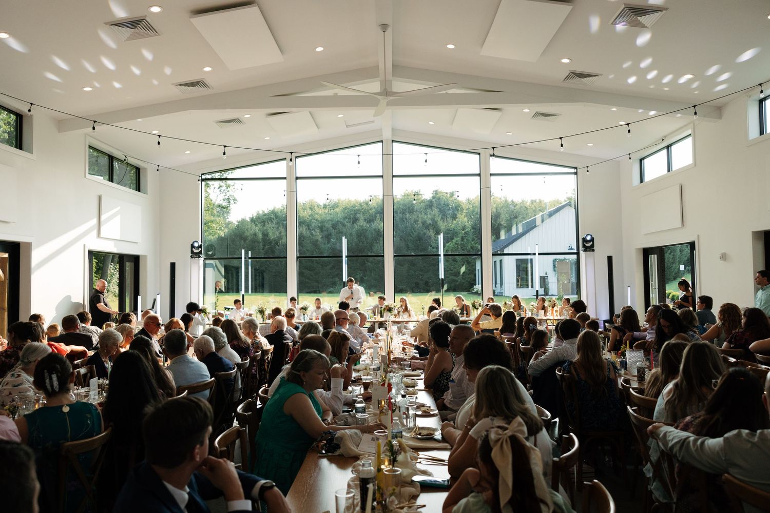 A crowded banquet hall filled with people seated at round tables during a formal event.